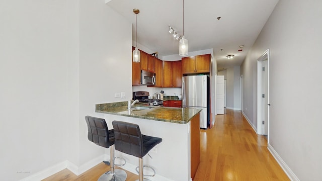 8 W Monroe St Unit 1507, Chicago, IL 60603 - kitchen featuring appliances with stainless steel finishes, light wood-style flooring, a peninsula, a breakfast bar area, and dark stone counters