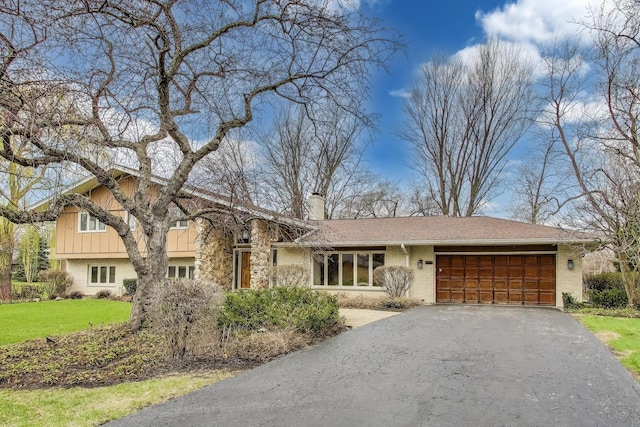 view of front of home with a chimney, driveway, an attached garage, a front yard, and brick siding