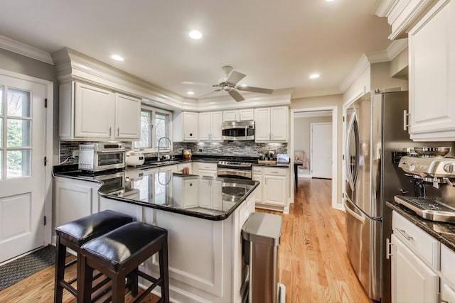 kitchen with a sink, a breakfast bar, crown molding, stainless steel appliances, and backsplash