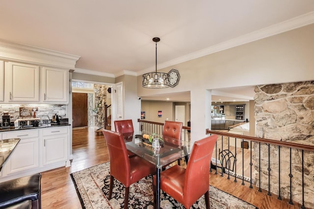 dining room with light wood finished floors, a notable chandelier, and ornamental molding