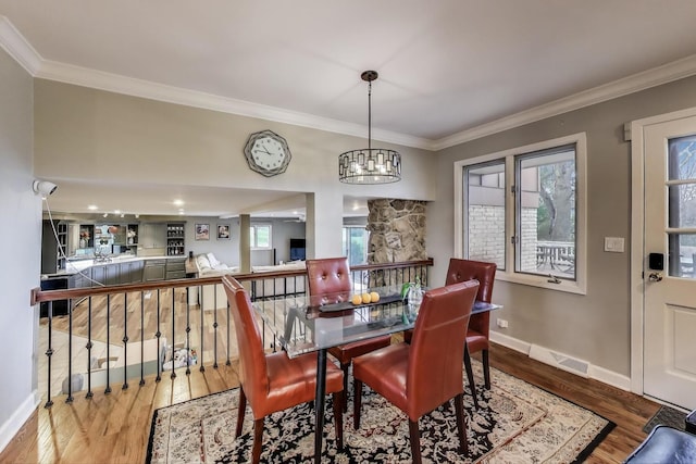 dining area with baseboards, an inviting chandelier, ornamental molding, visible vents, and wood finished floors