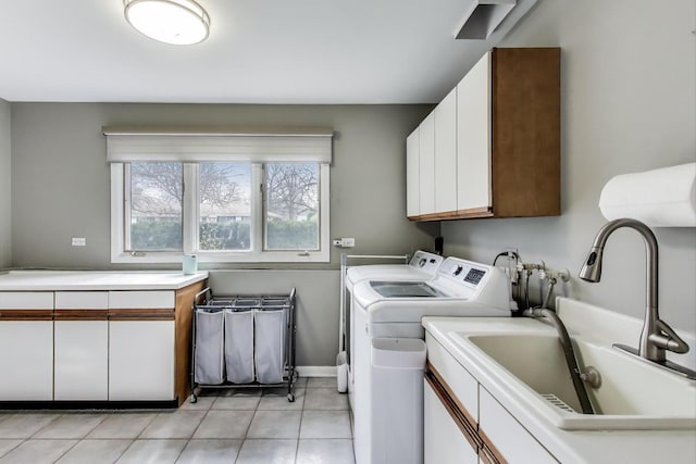laundry room featuring light tile patterned floors, baseboards, a sink, cabinet space, and washer and clothes dryer