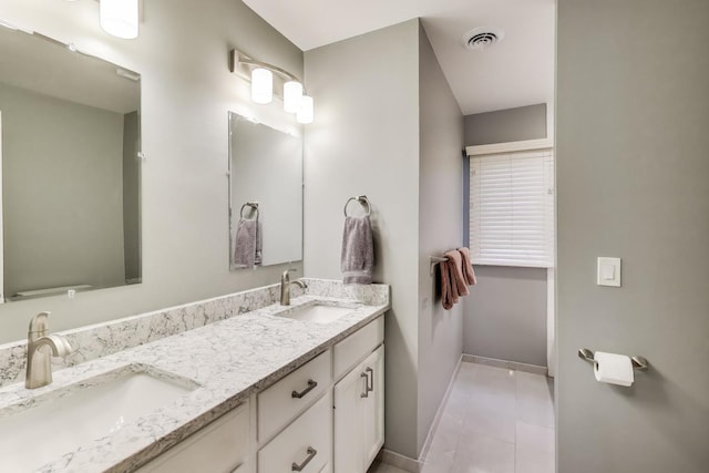 full bathroom featuring baseboards, double vanity, a sink, and visible vents
