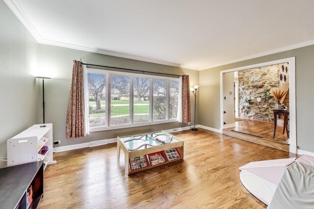 living area featuring baseboards, ornamental molding, and wood finished floors