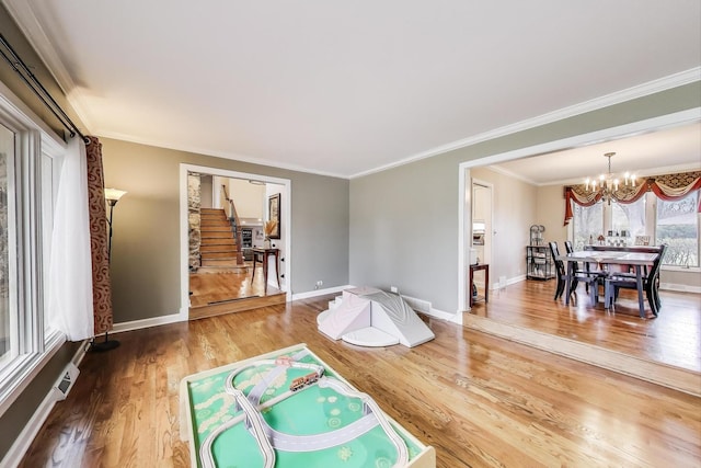 living area featuring baseboards, ornamental molding, a chandelier, wood finished floors, and stairs