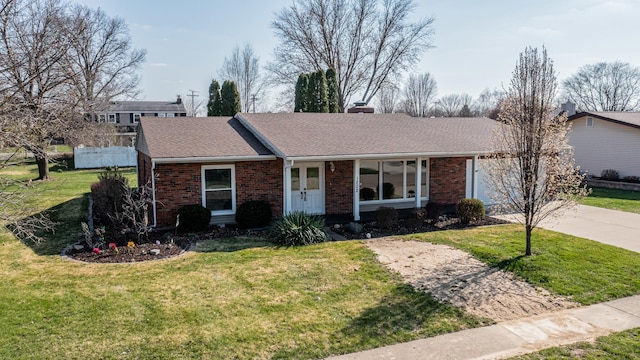 single story home featuring concrete driveway, a front lawn, and brick siding