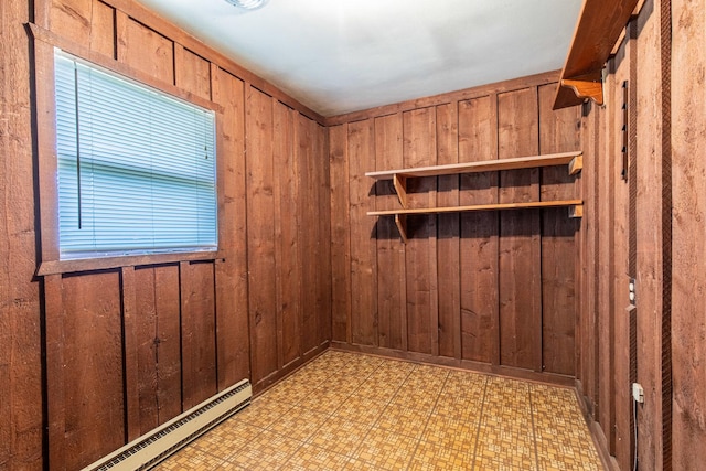 spare room with wood walls, baseboard heating, and light floors