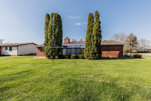 rear view of property featuring brick siding and a lawn