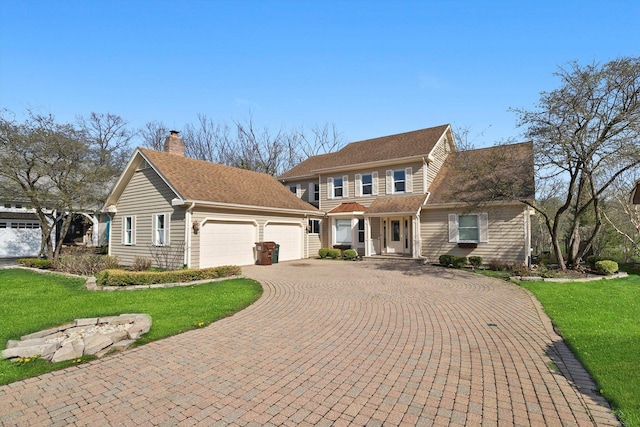 view of front of house featuring a chimney, a front yard, an attached garage, and decorative driveway