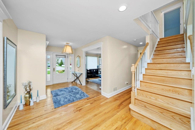 foyer entrance featuring wood finished floors, stairway, baseboards, and recessed lighting