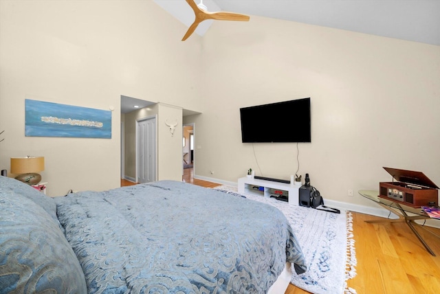 bedroom with baseboards, a high ceiling, a ceiling fan, and wood finished floors