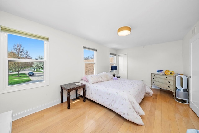 bedroom featuring baseboards, light wood-style flooring, and visible vents