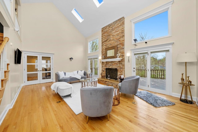 living room featuring french doors, a brick fireplace, high vaulted ceiling, wood finished floors, and a skylight