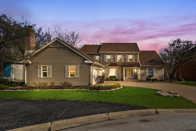 traditional home featuring a chimney, a front yard, and curved driveway