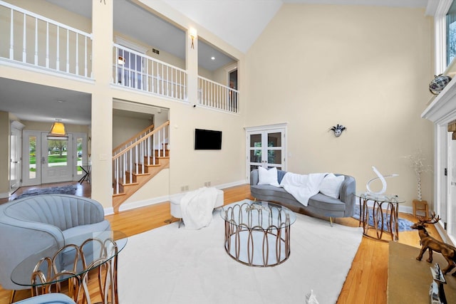 living area featuring french doors, baseboards, wood finished floors, stairway, and a high ceiling