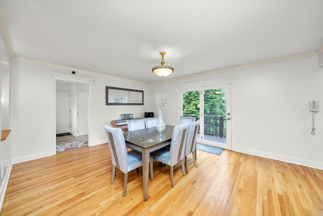 dining room with light wood finished floors, crown molding, and baseboards