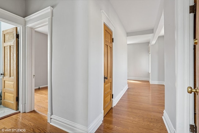 corridor featuring light wood-style floors and baseboards