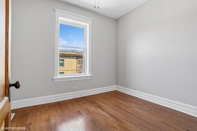 spare room featuring baseboards and wood finished floors