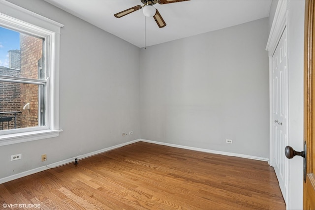 empty room with light wood-type flooring, a healthy amount of sunlight, baseboards, and a ceiling fan