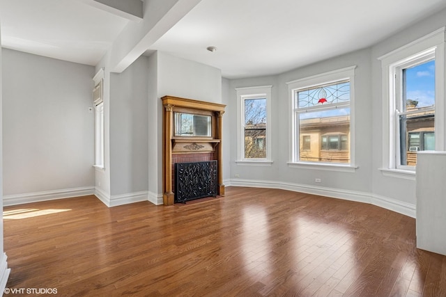 unfurnished living room with a fireplace with flush hearth, wood finished floors, and baseboards