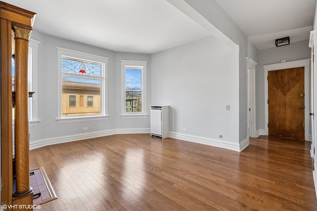 spare room featuring dark wood-type flooring, baseboards, and radiator