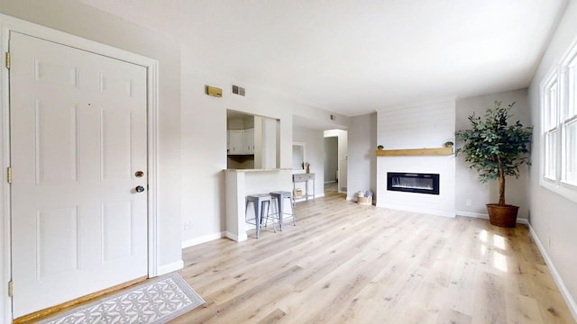 912 Crescent Dr Unit 2-4, Champaign, IL 61821 - unfurnished living room with light wood-style flooring, baseboards, and a glass covered fireplace