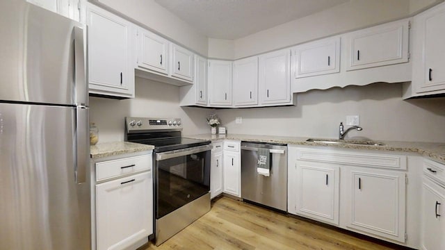 912 Crescent Dr Unit 2-4, Champaign, IL 61821 - kitchen with stainless steel appliances, a sink, white cabinets, light wood-style floors, and light stone counters