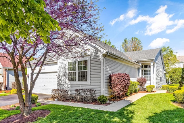 view of property exterior with an attached garage, a yard, and aphalt driveway