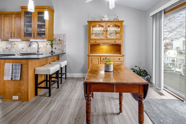 dining room with light wood-style flooring, vaulted ceiling, visible vents, and ceiling fan