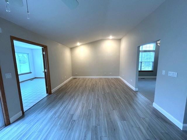 unfurnished room with baseboards, vaulted ceiling, and wood finished floors