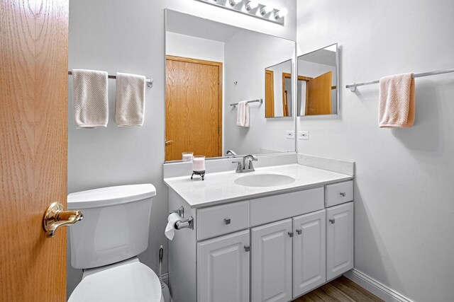 bathroom featuring toilet, vanity, and baseboards