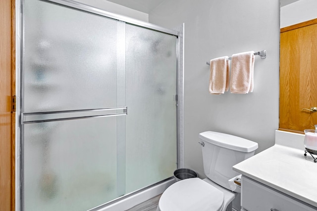 bathroom featuring toilet, a stall shower, and vanity