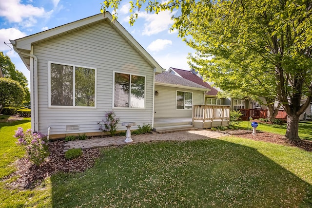 rear view of house featuring crawl space, a deck, and a lawn