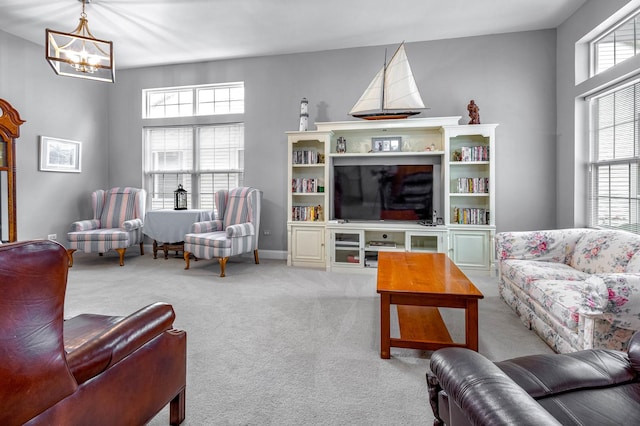 carpeted living room with a chandelier and baseboards