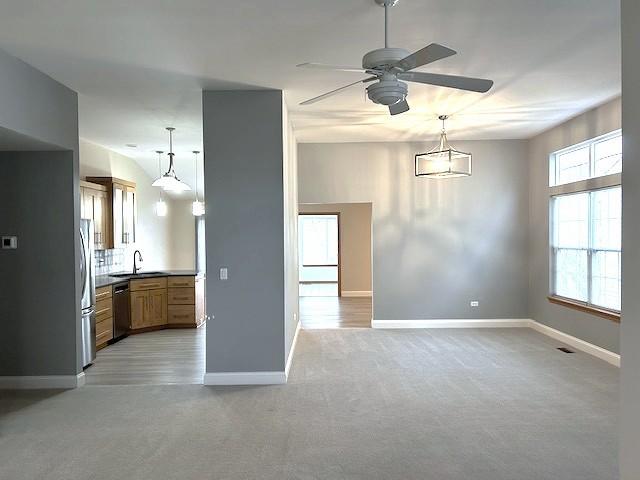 interior space featuring brown cabinetry, a ceiling fan, appliances with stainless steel finishes, a sink, and baseboards
