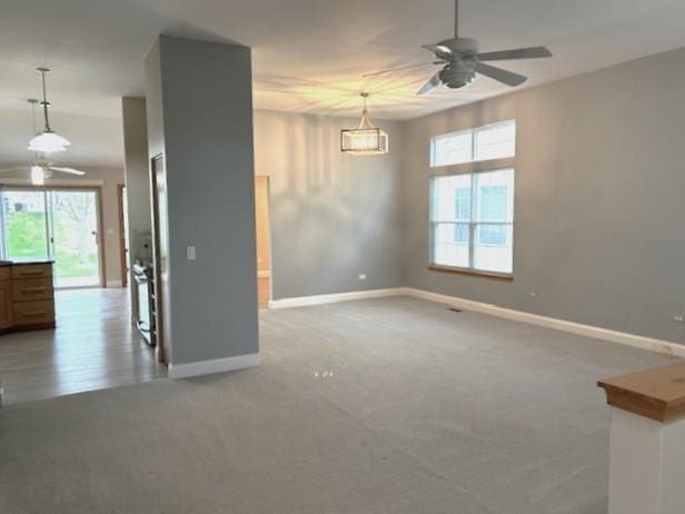 unfurnished living room with baseboards, a ceiling fan, and carpet