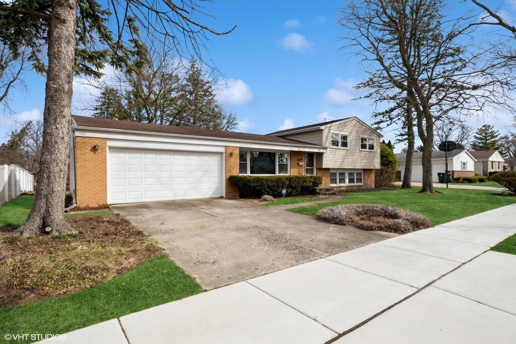 2208 N Champlain St, Arlington Heights, IL 60004 - tri-level home with concrete driveway, a front lawn, an attached garage, brick siding, and fence