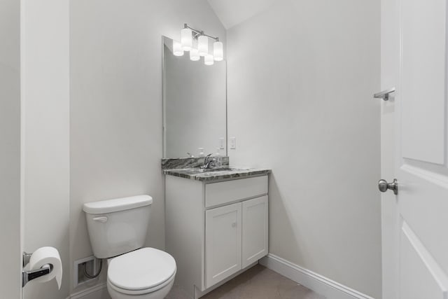 half bath featuring toilet, vaulted ceiling, vanity, and baseboards