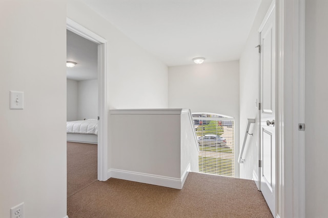 hall featuring carpet flooring, baseboards, an upstairs landing, and heating unit