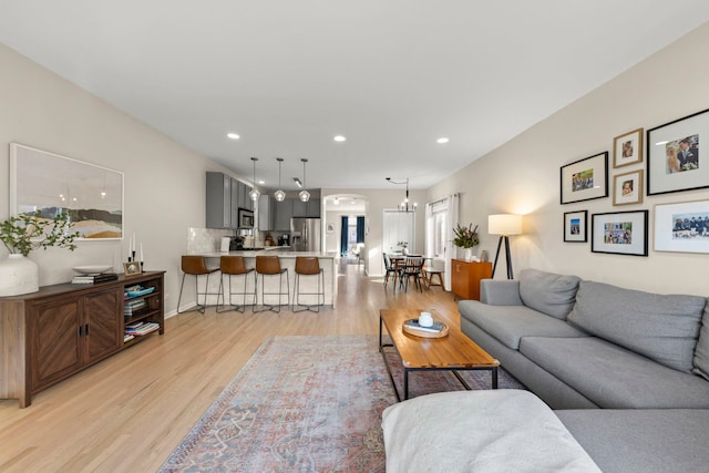living room with arched walkways, recessed lighting, light wood-type flooring, and baseboards