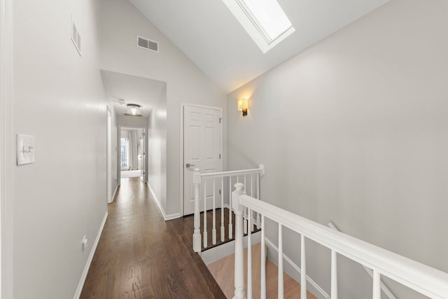 corridor with a skylight, wood finished floors, visible vents, and an upstairs landing