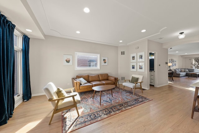 living room featuring recessed lighting, arched walkways, light wood-type flooring, and baseboards