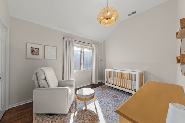bedroom with baseboards, visible vents, a nursery area, lofted ceiling, and wood finished floors
