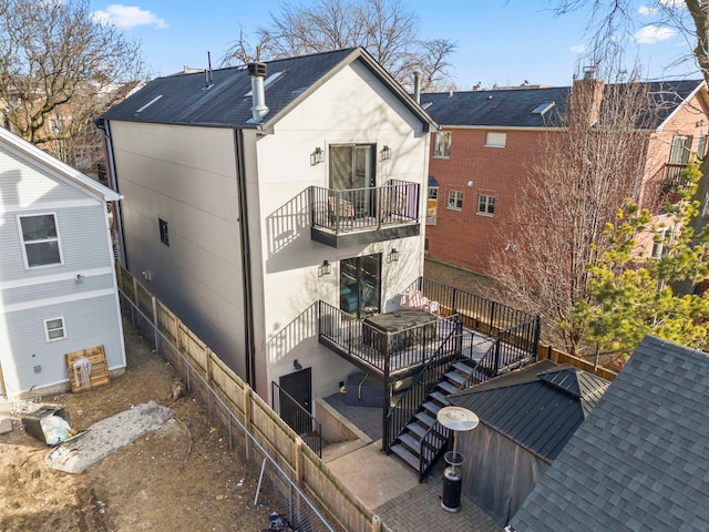 rear view of property with stairway, a balcony, and a shingled roof