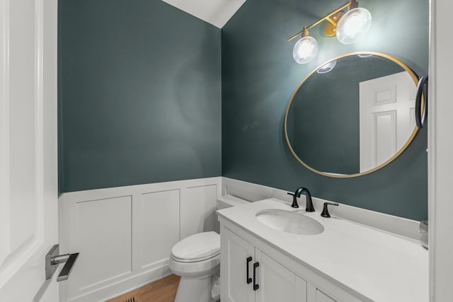 bathroom featuring toilet, a wainscoted wall, vanity, and wood finished floors