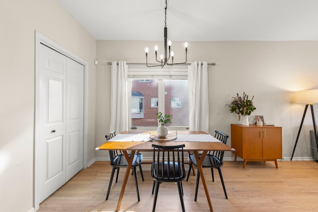 dining area with light wood-style flooring, a chandelier, and baseboards