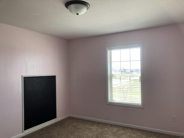 empty room featuring carpet flooring, baseboards, and plenty of natural light