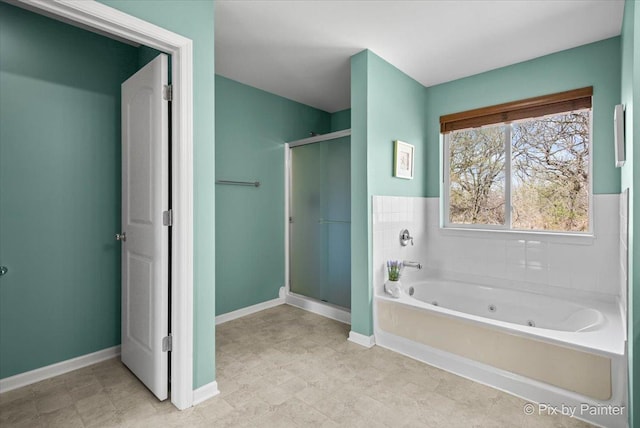 bathroom with a shower stall, a jetted tub, and baseboards