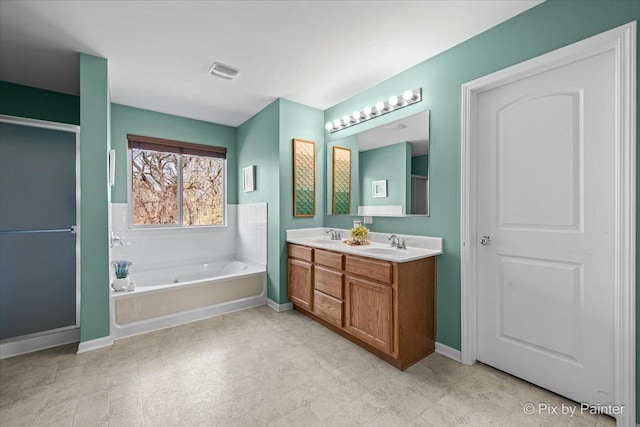 full bathroom with a sink, double vanity, visible vents, baseboards, and a garden tub