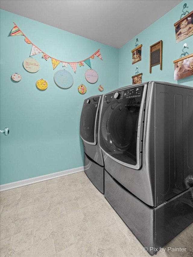 washroom featuring tile patterned floors, washer and dryer, laundry area, and baseboards